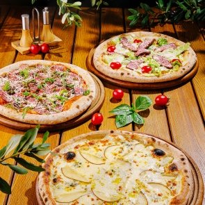 delicious-selection-of-gourmet-pizzas-on-wooden-ta-XM4XSDV.jpg
